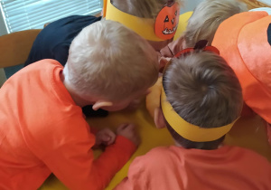 Na zdjęciu widać dzieci które wydrążają dynię. Zabawa sensoryczna.