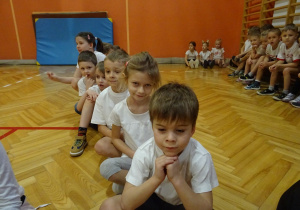 Na zdjęciu widać dzieci które siedzą na sali i czekają na zawody sportowe.