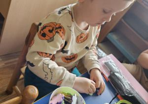 Na zdjęciu widać dziecko które robi króliczka wielkanocnego z owsem wsadzonym samodzielnie.