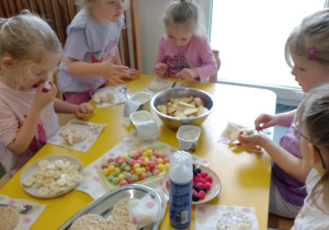 Na zdjęciu widać dzieci które układają kompozycję kwiatową na wafelkach według własnego pomysłu.