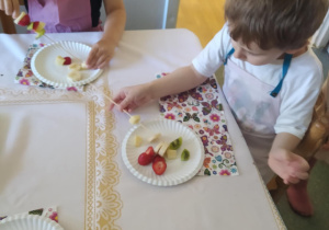 Na zdjęciu widać chłopca który je sałatkę owocową.