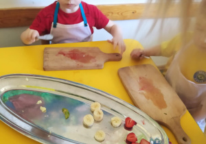 Na zdjęciu widać chłopca który kroi sałatkę owocową.