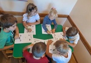 Na zdjęciu widać dzieci które wykonują zadania w kartach pracy.