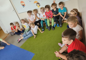Na zdjęciu widać dzieci które obserwują zajęcia pokazowe Judo.