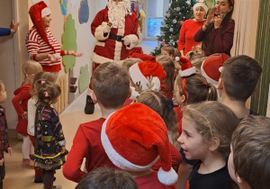 Na zdjęciu widać dzieci i Św Mikołaja który wręcza prezenty.