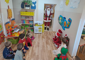 Na zdjęciu widać dzieci i Św Mikołaja który wręcza prezenty.