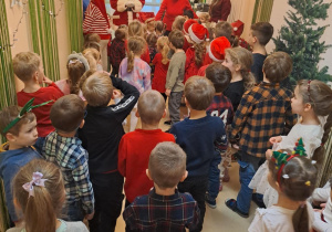 Na zdjęciu widać dzieci i Św Mikołaja który wręcza prezenty.