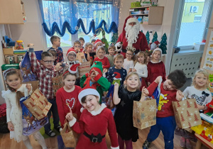 Na zdjęciu widać dzieci i Św Mikołaja który wręcza prezenty.