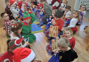 Na zdjęciu widać dzieci i Św Mikołaja który wręcza prezenty.