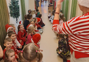 Na zdjęciu widać dzieci i Św Mikołaja który wręcza prezenty.