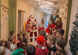 Na zdjęciu widać dzieci i Św Mikołaja który wręcza prezenty.