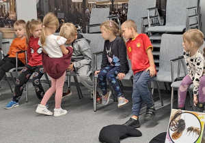 Na zdjęciu widać dzieci które oglądają owady które pokazuje dziewczynka.