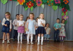 Cztery dziewczynki na scenie recytują lub śpiewają pokazując trzy palce.