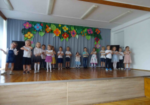 Grupa dzieci tańczy na scenie, wykonując tak zwany "młynek".