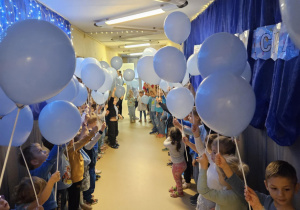 Na zdjęciu widać dzieci które trzymają w rękach niebieskie balony z Okazji Praw Dziecka.