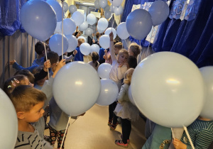 Na zdjęciu widać dzieci które trzymają w rękach niebieskie balony z Okazji Praw Dziecka.