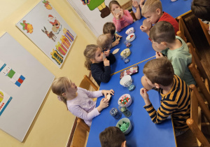 Na zdjęciu widać dzieci które ozdabiają bombkę bożonarodzeniową.