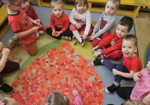 Na zdjęciu widać dzieci które pokazują serce z okazji walentynek przez siebie wykonane.