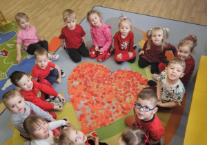 Na zdjęciu widać dzieci które pokazują serce z okazji walentynek przez siebie wykonane.