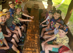 Dzieci siedzą przy drewnianym stole piknikowym podczas wycieczki do Konarzewa.
