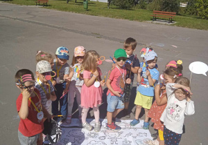 Dzieci stojąc w półkolu prezentują medale z okazji Dnia Przedszkolaka