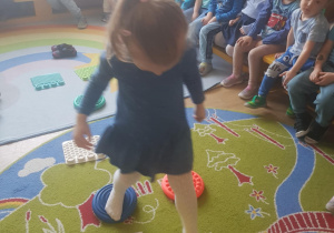 Na zdjęciu widać dzieci które będą przechodzić po podkładkach sensorycznych.