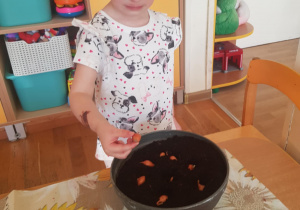 Na zdjęciu widać dziecko które sadzi cebulę.