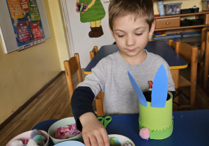 Na zdjęciu widać dziecko które robi króliczka wielkanocnego z owsem wsadzonym samodzielnie.