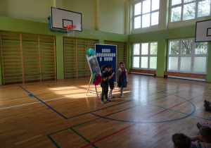 Na zdjęciu widać dzieci na scenie które recytują wiersz.