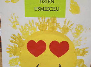 Żółte serce z promieniami z odciśniętych dłoni dzieci. W tle napis 6 październik 2023, Światowy dzień uśmiechu.