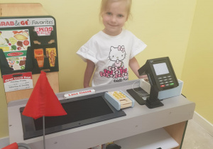Na zdjęciu widać dziewczynkę która bawi się w sklep.