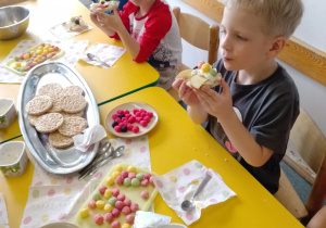 Na zdjęciu widać dzieci które układają kompozycję kwiatową na wafelkach według własnego pomysłu.
