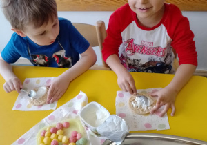 Na zdjęciu widać dzieci które układają kompozycję kwiatową na wafelkach według własnego pomysłu.