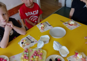 Na zdjęciu widać dzieci które układają kompozycję kwiatową na wafelkach według własnego pomysłu.