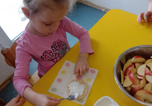 Na zdjęciu widać dziecko które układa kompozycję kwiatową na wafelkach według własnego pomysłu.