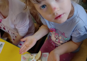 Na zdjęciu widać dziecko które układa kompozycję kwiatową na wafelkach według własnego pomysłu.