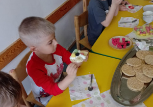Na zdjęciu widać dziecko które układa kompozycję kwiatową na wafelkach według własnego pomysłu.