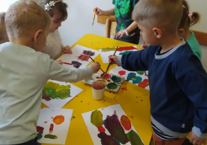 Na zdjęciu widać dzieci które malują farbami.