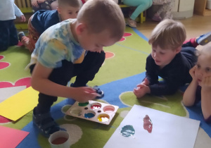 Na zdjęciu widać dzieci które malują farbami.