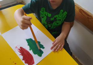 Na zdjęciu widać dzieci które malują farbami.