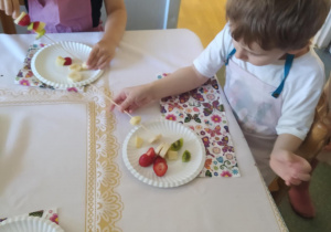 Na zdjęciu widać chłopca który je sałatkę owocową.