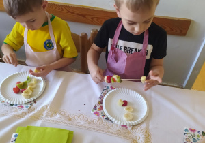 Na zdjęciu widać dzieci które jedzą sałatkę owocową.