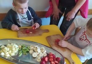 Na zdjęciu widać dzieci które kroją sałatkę owocową.