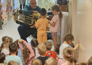 Na zdjęciu widać dzieci które oglądają koncert Pan gra na trąbce.