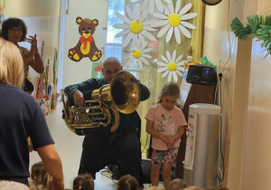 Na zdjęciu widać dzieci które oglądają koncert Pan gra na trąbce.