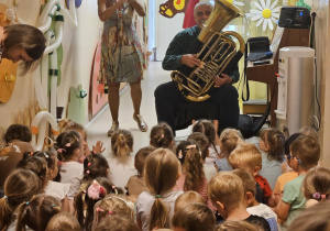 Na zdjęciu widać dzieci które oglądają koncert Pan gra na trąbce.
