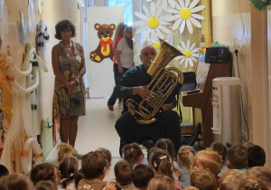 Na zdjęciu widać dzieci które oglądają koncert Pan gra na trąbce.