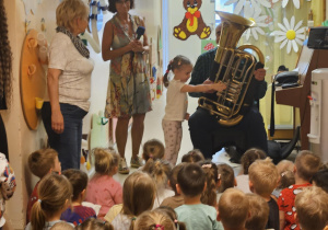 Na zdjęciu widać dzieci które oglądają koncert Pan gra na trąbce.