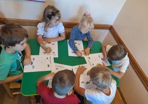 Na zdjęciu widać dzieci które wykonują zadania w kartach pracy.