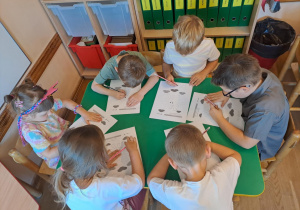 Na zdjęciu widać dzieci które wykonują zadania w kartach pracy.